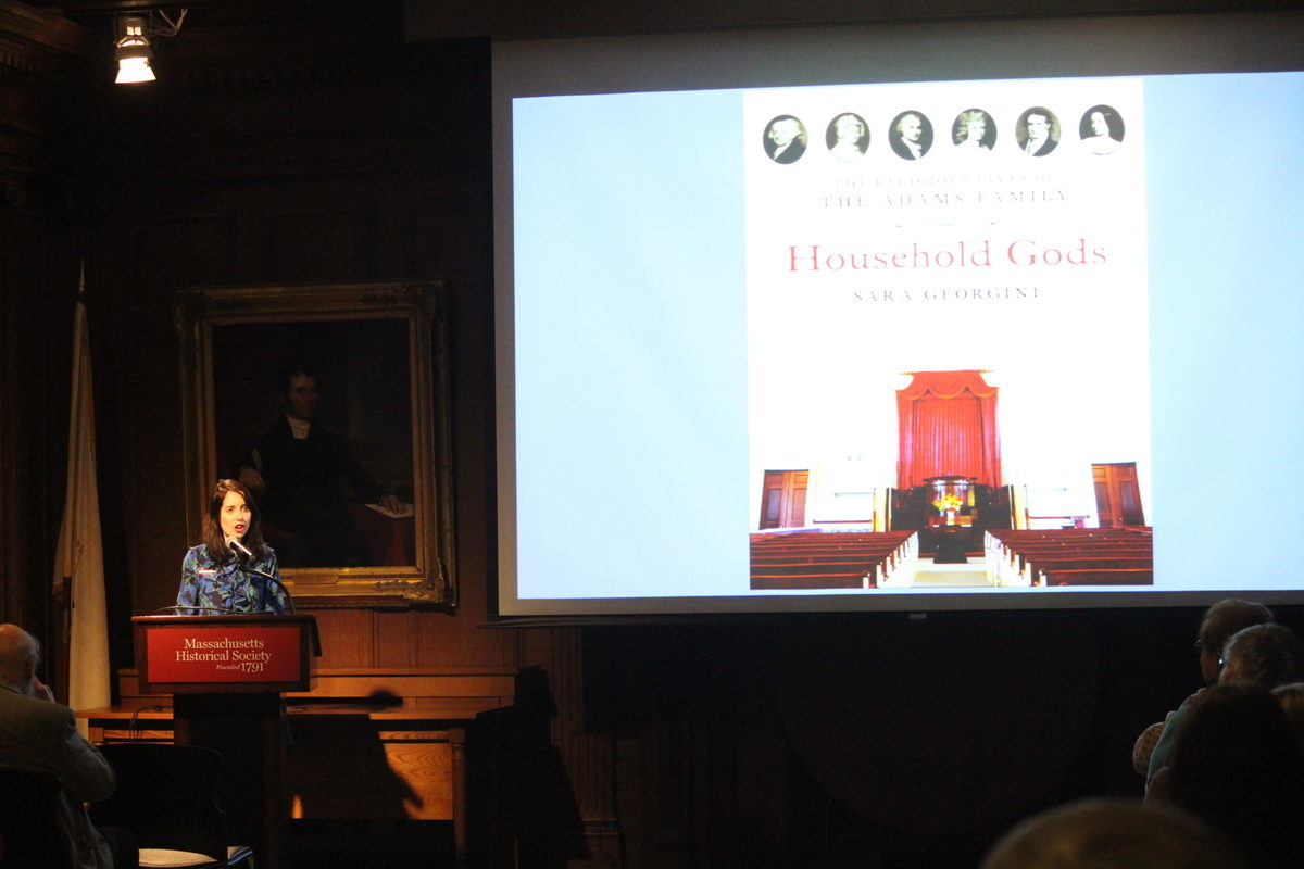 Woman standing at a podium speaking to a seated audience